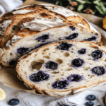 Lemon Blueberry Sourdough Bread with lemon zest and fresh blueberries on a wooden table.